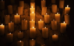 Rows of burning candles surrounded by melted candle wax